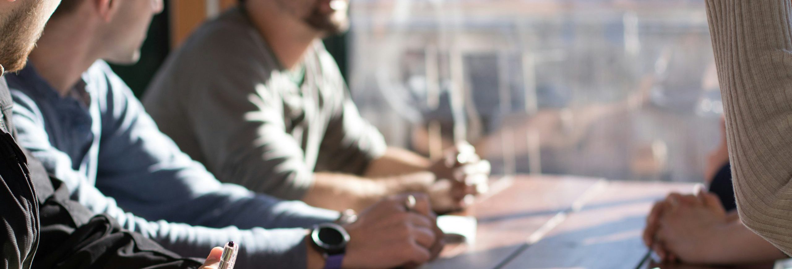 Headerbild: Eine Gruppe an Personen sitzt an einem Tisch.